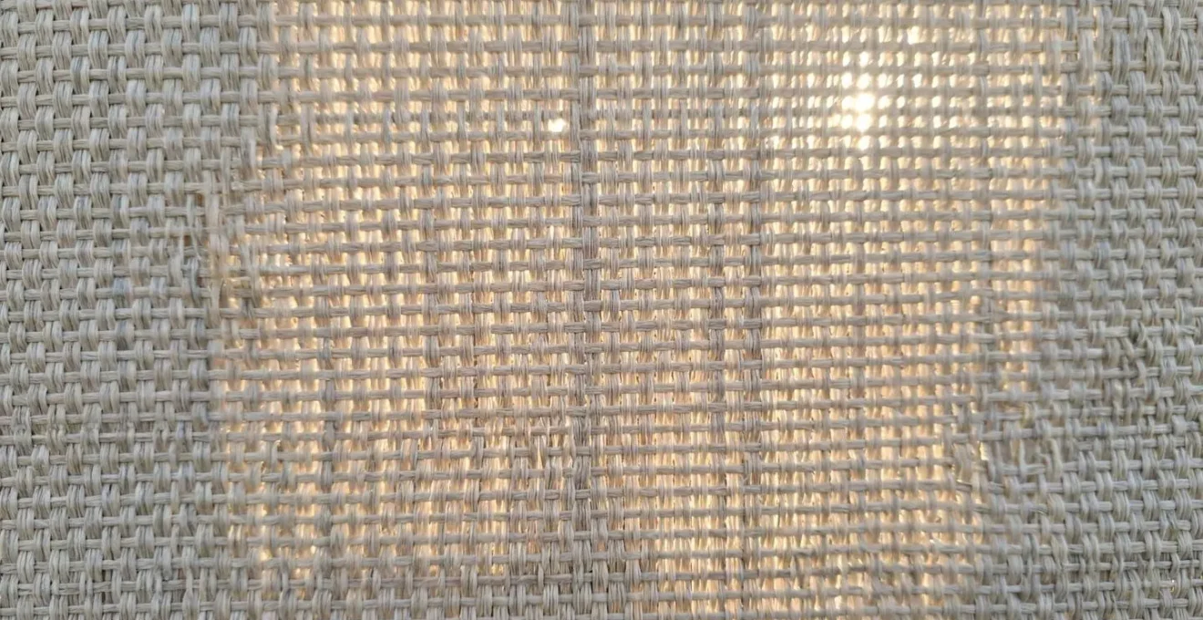 Detalle de tejido acrílico de toldo con luz natural atravesándolo mostrando textura del material